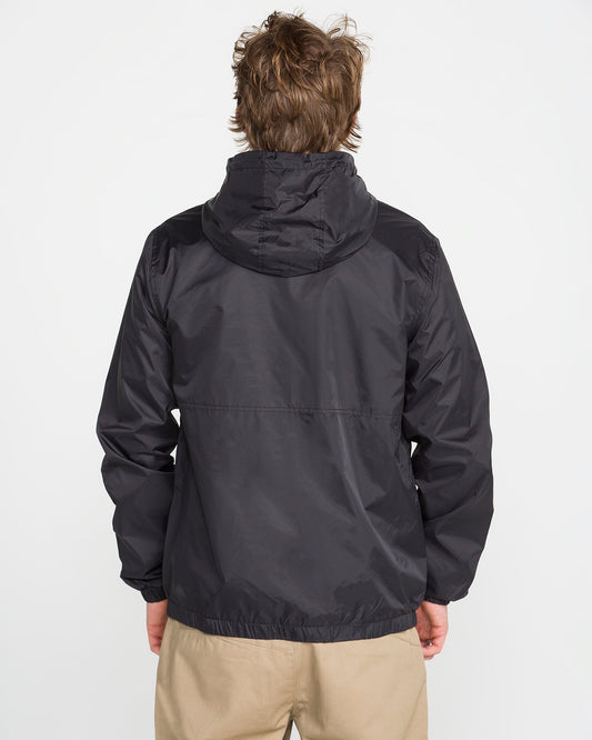 A person with light brown hair is seen from the back, wearing Volcom's Men's Ermont Jacket in black and beige pants, standing against a plain white background.