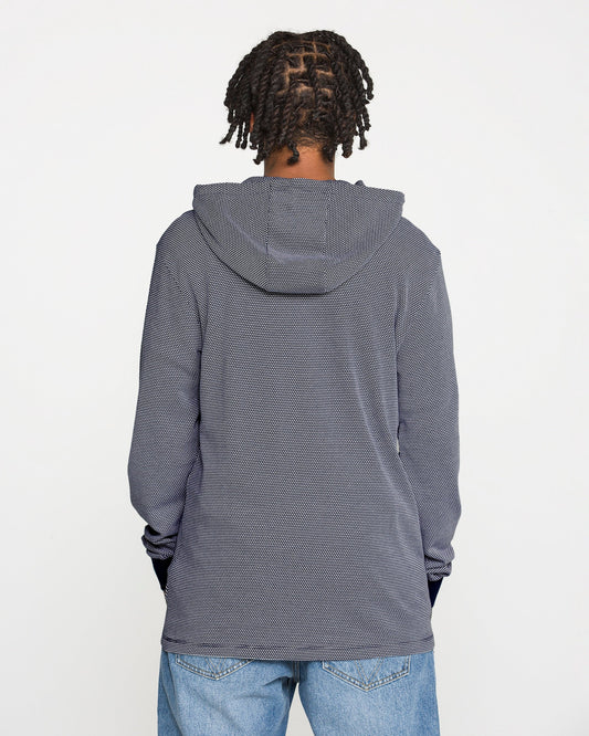 A person with short, twisted braids wears the Volcom Men's Rowan Thermal Long Sleeve Shirt in gray, paired with blue jeans, standing with their back to the camera against a plain white background.