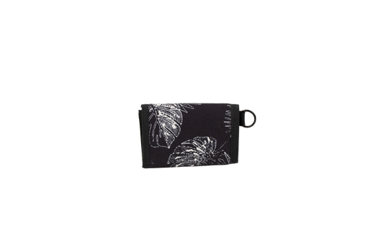 A black cotton canvas wallet with a white leaf and flower pattern, folded closed, featuring a small black loop on the right side, is displayed against a plain white background. The Men’s Box Stone Wallet from Volcom combines style and practicality in a compact design.