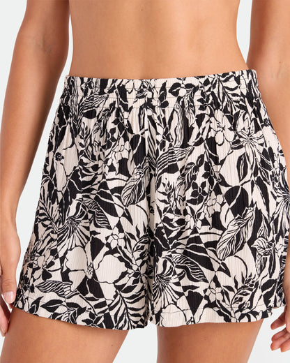 A woman wears Volcom's Women's Funtastical Viscose Shorts featuring a black and white floral print and an elasticated waistband, shown from waist to mid-thigh against a plain background.