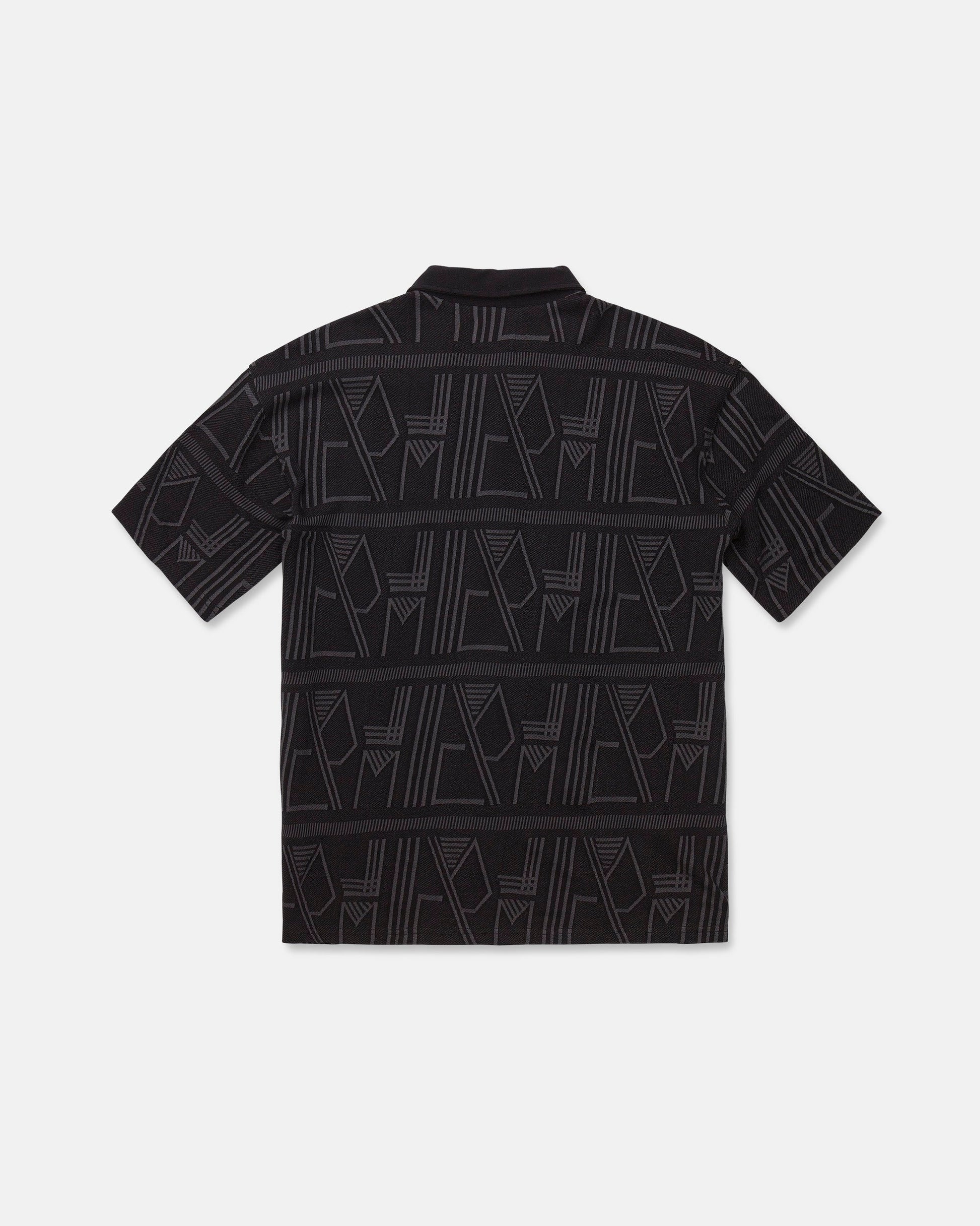 The Men's Stone Optix Polo by Volcom is a black short-sleeve shirt with an abstract geometric pattern in gray, featuring yarn-dyed jacquard lines and shapes across the fabric. Displayed flat to show the back side against a white background, this polo features a boxy fit.
