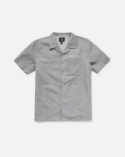 The Volcom Men's Otis Stone Short Sleeve Tee is a light gray, boxy-fit tee with a collar, made from textured fabric. It has a single chest pocket with "Welcome" embroidered above it in white.