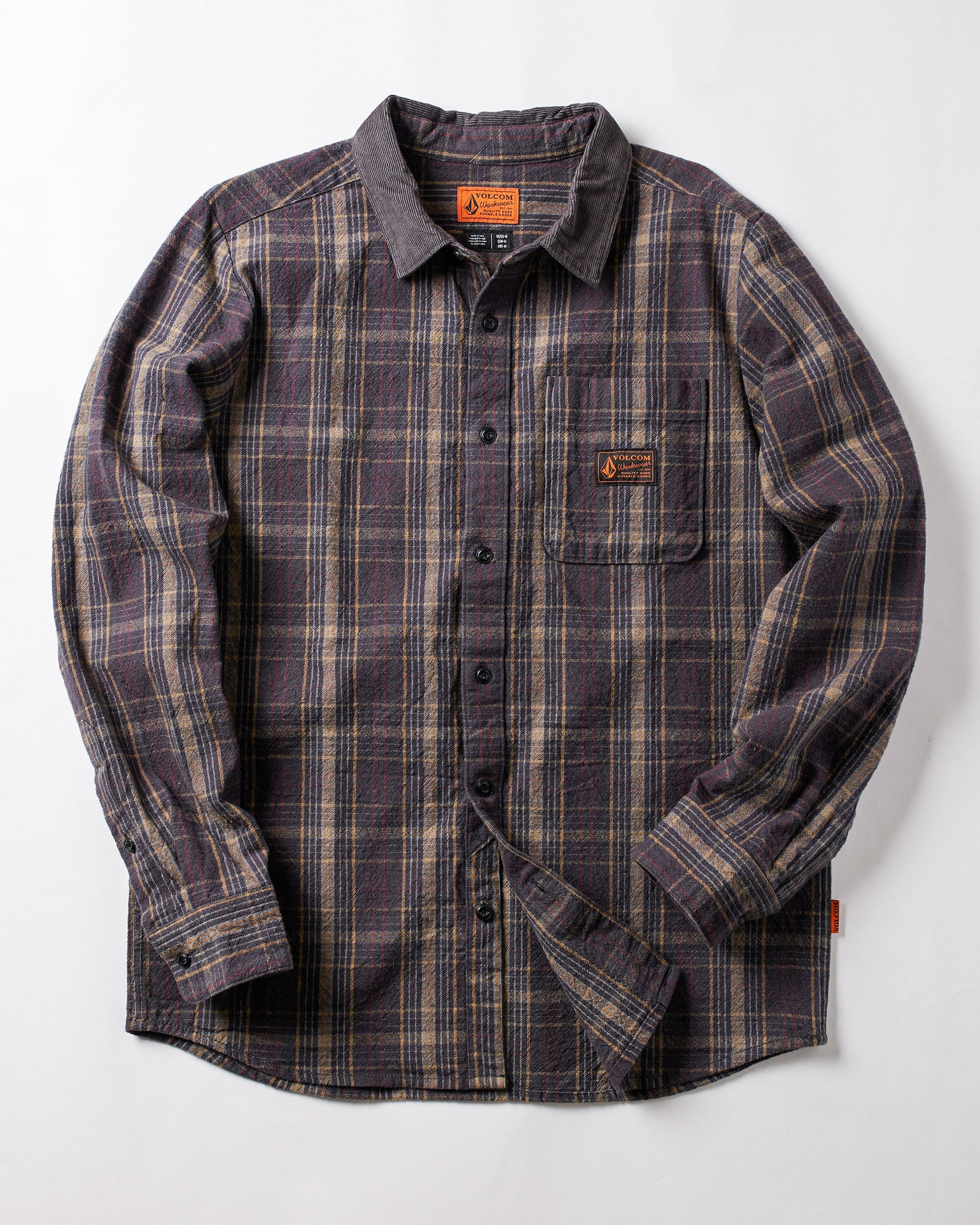 The Volcom Men's Stonevise Plaid Long Sleeve is a workwear-style flannel shirt with purple, gray, and beige plaid, chest pocket, small orange label, and button-up front. Displayed flat on a white background.