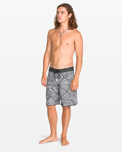 Man wearing black and white patterned swim shorts on a white background