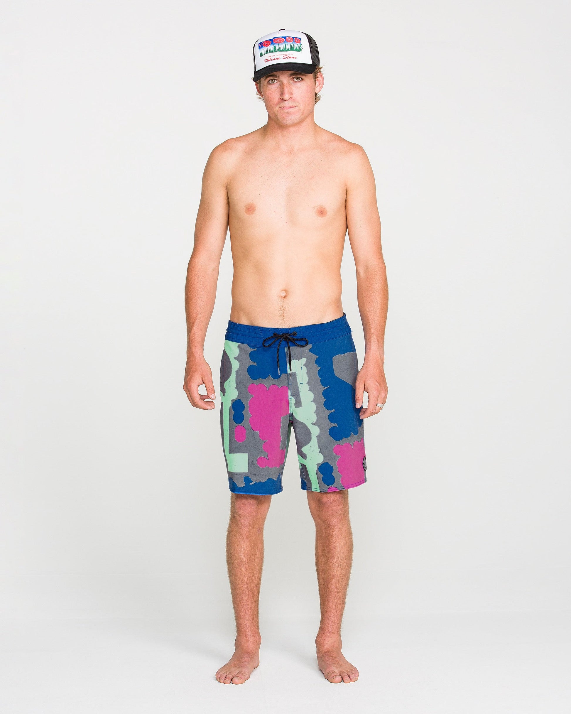 A shirtless person wearing a colorful hat and Volcom Men's Featured Artist Antonio Carrau Stoney Trunks stands facing forward against a plain white background.