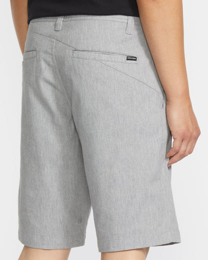 A man seen from behind wears light gray Volcom Men's Frickin Modern Stretch Shorts with back pockets and a small black logo tag above the right pocket. These cotton stretch shorts offer comfort and style.