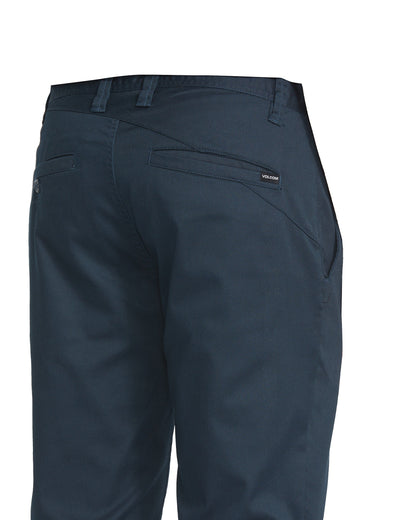 A close-up of the back and side of Volcom Men's Frickin Modern Stretch Pants in dark blue, featuring belt loops, two back pockets, and a small Volcom tag above the right pocket.