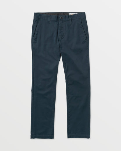The Volcom Men's Frickin Modern Stretch Pants are slim-fit dark navy blue twill pants with side pockets, button and zip closure, and belt loops, shown on a white background.