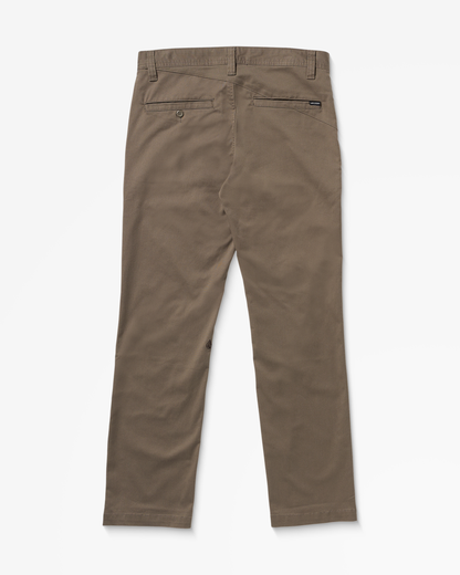 Back view of Volcom Men's Frickin Modern Stretch Pants in brown khaki, with belt loops, two back pockets (one buttoned, one labeled), made from recycled polyester, straight leg cut, displayed flat on a white background.