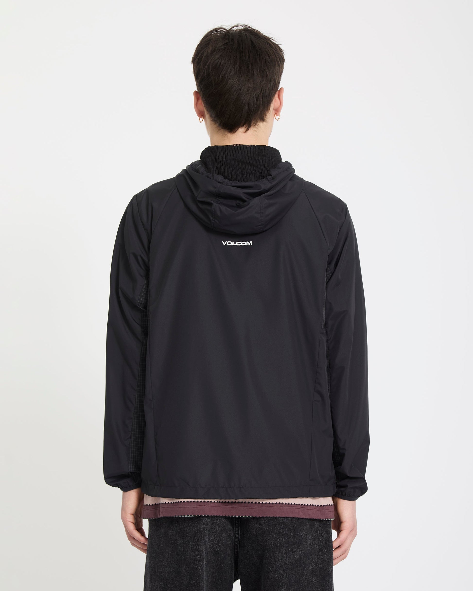 A person with short dark hair, wearing the Volcom Men's Wavern Jacket with a logo on the back, stands facing away from the camera against a plain white background.