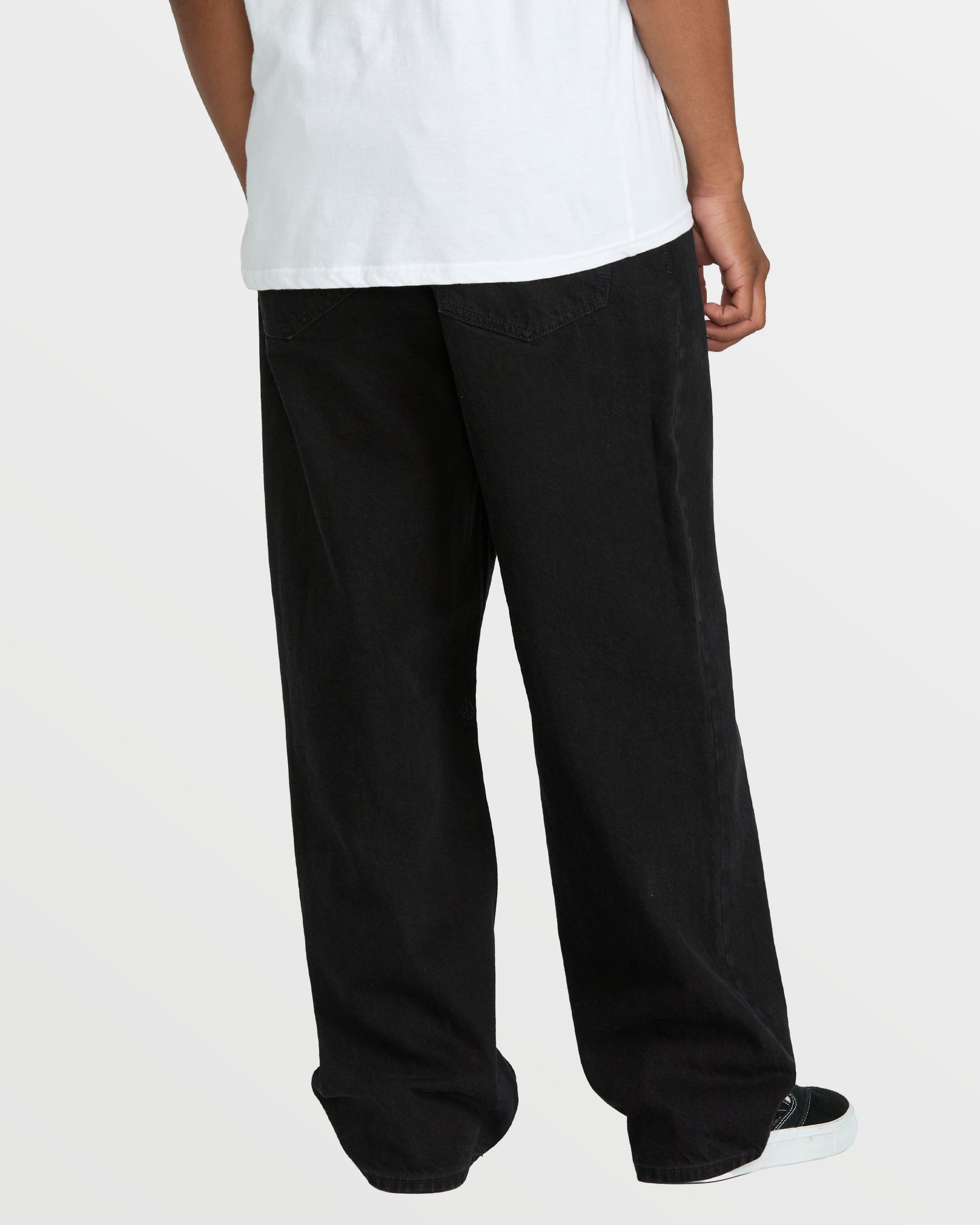 A person wearing Volcom Men's Billow Denim, a loose fit style featuring classic black pants.