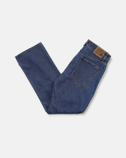 Men's Pipe Dreams Denim Pants by Volcom, crafted from dark indigo denim in a relaxed straight fit, are folded neatly to display the back pocket and brown leather Volcom brand patch on the waistband, set against a plain white background.