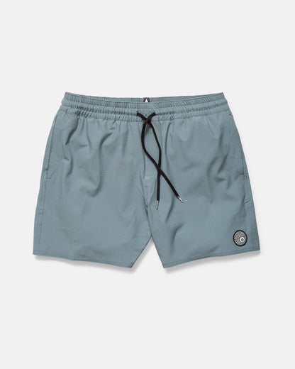 The Volcom Men's Lido Solid 16" Trunk in light blue features an elastic waistband, black drawstring, side pockets, and a small circular patch near the left hem. The shorts are displayed flat on a plain white background.