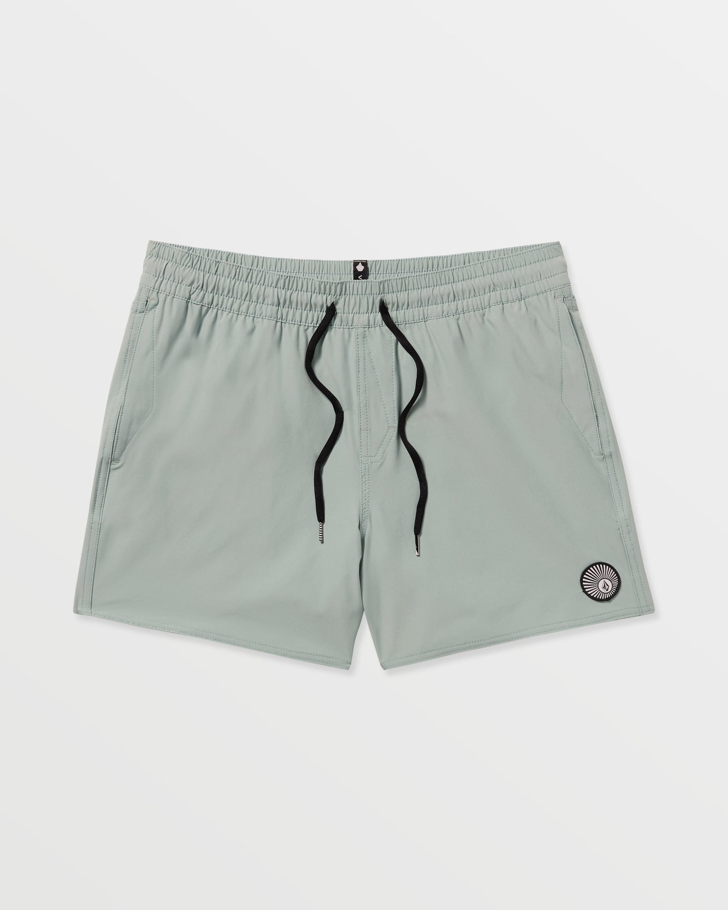 Volcom Men's Lido Solid 16" Trunks in light gray feature a black drawstring, two side pockets, and a small circular patch near the left hem. Made from recycled polyester with 2-way stretch, shown on a plain white background.