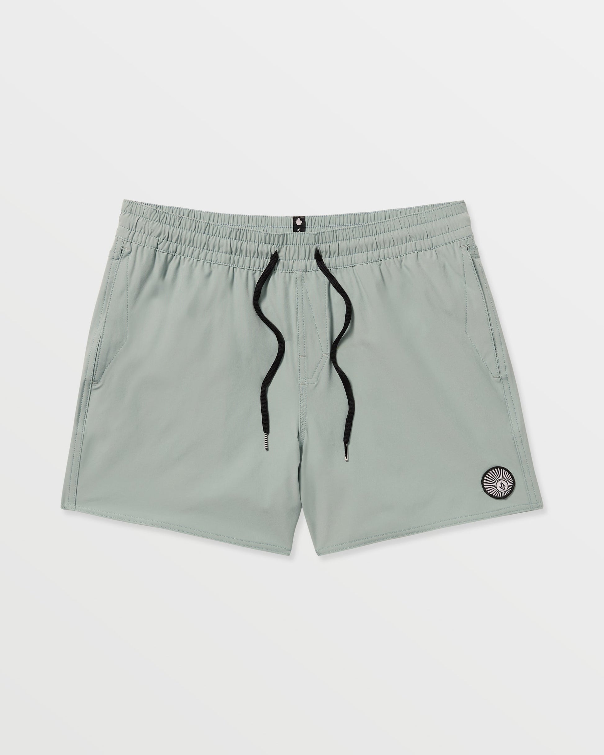 Volcom Men's Lido Solid 16" Trunks in light gray feature a black drawstring, two side pockets, and a small circular patch near the left hem. Made from recycled polyester with 2-way stretch, shown on a plain white background.