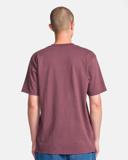 A person with short hair stands with their back to the camera, wearing a plain maroon Men's Yoink Short Sleeve Tee by Volcom and blue jeans against a light background.