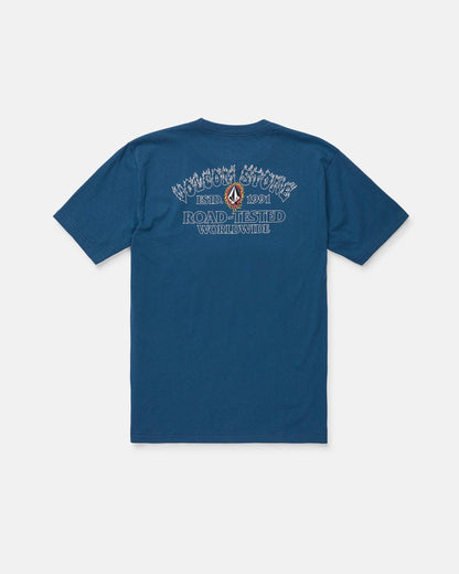 The Volcom Men's Ringafire Short Sleeve Tee, shown from the back in blue, is crafted from premium ring spun cotton for a soft, durable feel. This heavy-weight t-shirt features decorative white and blue "Road-Tested Worldwide" text, a small graphic, and additional branding above and below it.