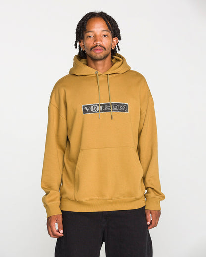 A person wearing the Volcom Men's Super Stoned Pullover in mustard yellow, crafted from brushed-back fleece, paired with black pants, stands against a plain white background and looks at the camera.