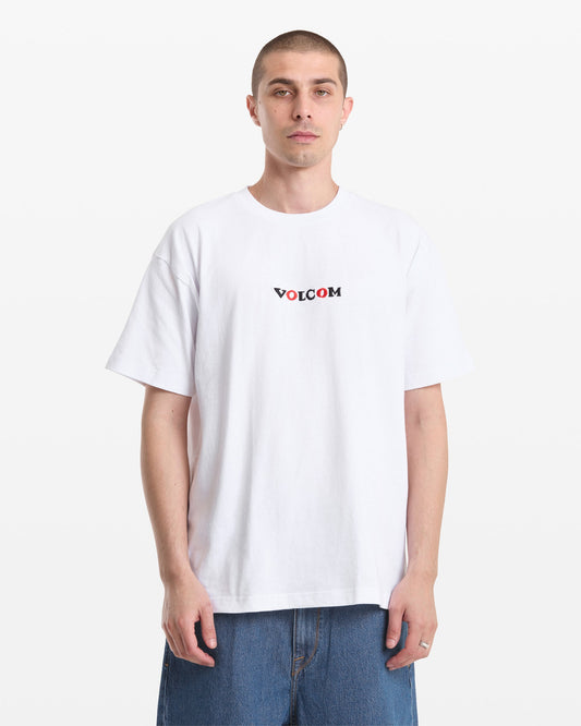 A man with short hair wears the Volcom Men's Featured Artist Seth Conboy Loose Short Sleeve Tee and blue denim shorts, standing against a plain white background.