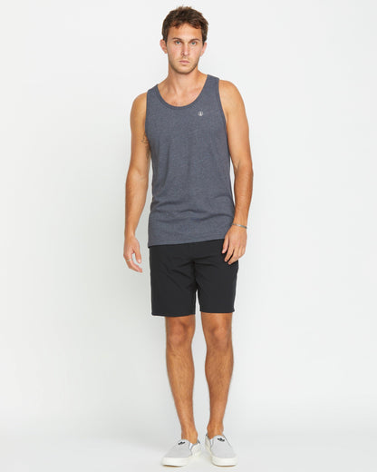 A man with short brown hair and a neutral expression wears the Volcom Men's Solid Heather Tank, paired with black shorts and light gray slip-on shoes, standing against a plain white background.
