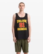 A man with short hair wears the Volcom Men's Swish Tank, a loose black top with "Volcom 91 Hawaii" in yellow and red, paired with olive cargo shorts, standing against a plain white background.