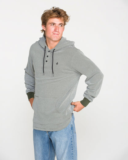 A person wearing the Volcom Men's Rowan Thermal Long Sleeve Shirt in gray, styled with blue jeans, stands with one hand on their hip and looks off to the side against a plain white background.