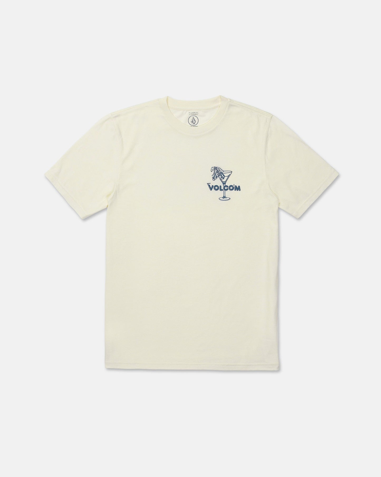 The Men's Dive Bar Short Sleeve Tee by Volcom features a cream color with a modern fit and short sleeves. Made from a soft ringspun cotton-poly blend, this t-shirt displays a small blue "VOLCOM" graphic on the left chest and showcases an illustration of a woman sitting on the rim of a cocktail glass.