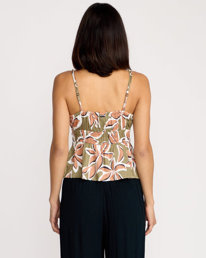 A woman with shoulder-length dark hair is seen from the back, wearing the Volcom Women's Psychonic Cami with a floral print and adjustable straps, paired with black pants against a plain white background.