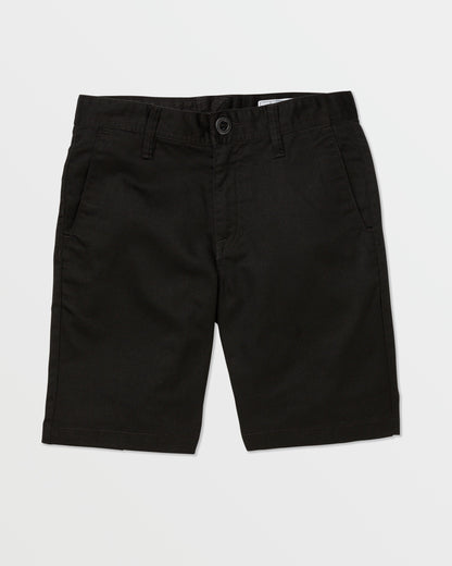 A pair of black Volcom Kids' Frickin Chino Shorts 16" with a modern fit, front pockets, belt loops, and a button closure is laid flat on a white background.