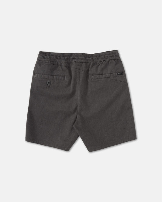 Back view of Volcom Kids' Big Boys' Frickin Elastic Waist Shorts in dark gray, featuring two back pockets (one with button) and a black brand tag above the right pocket. Made from recycled poly-cotton, shorts shown laid flat on a light surface.
