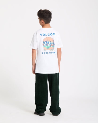 A boy faces away, wearing the Kids' Burgstone Pocket Tee—an organic cotton white T-shirt with burger and ocean art plus "VOLCOM COOL CLUB" text—paired with dark green pants and black shoes, set against a plain white background.