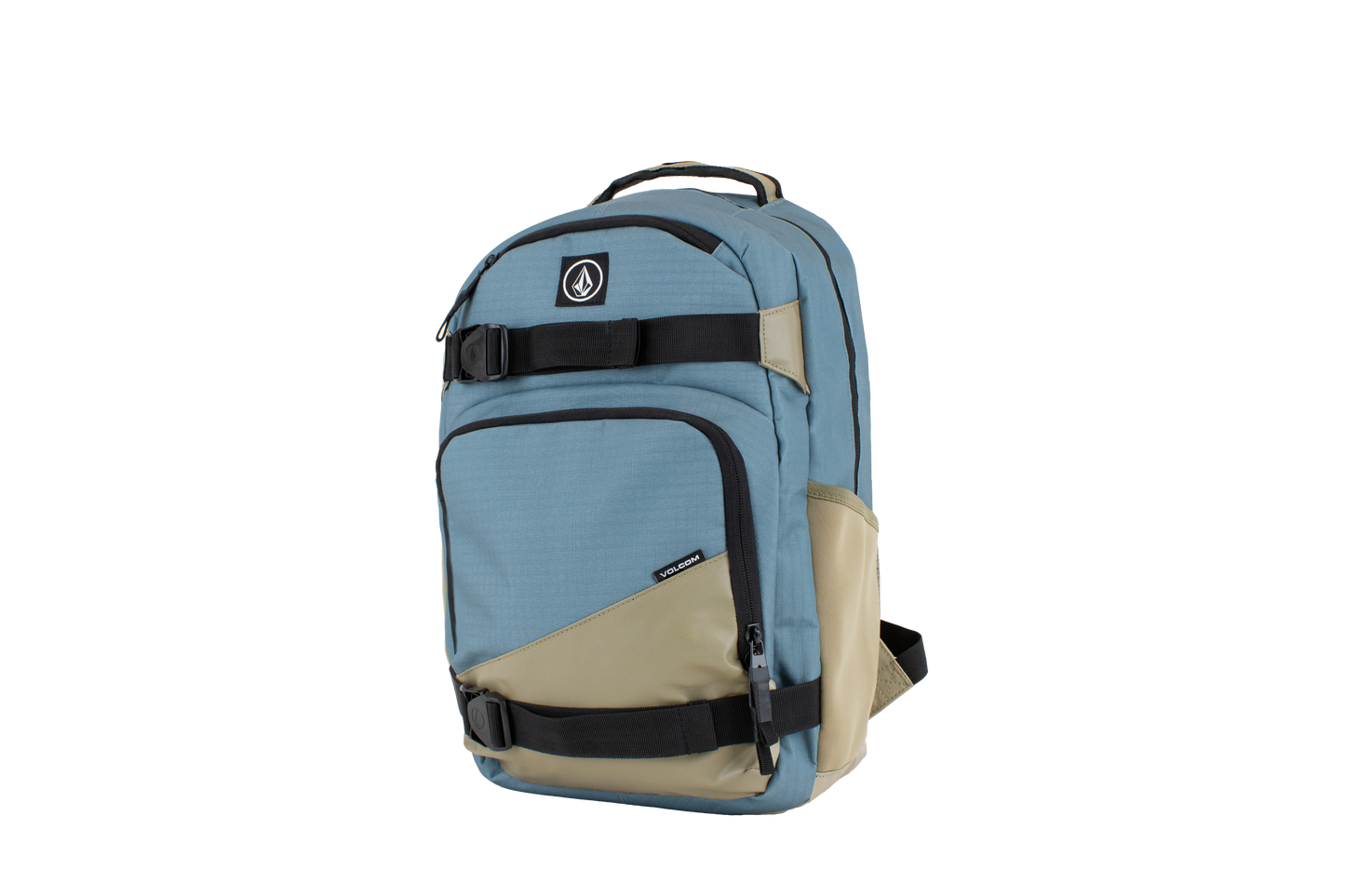 The Volcom Men's Grindstone Skate Backpack is shown standing upright against a plain white background. It features a blue and beige color scheme with multiple zippered compartments, black ergonomic straps, a padded laptop sleeve, a top handle, and a circular Volcom logo patch on the front.