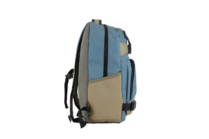 The Volcom Men's Grindstone Skate Backpack in blue and tan is displayed from the side on a plain white background, highlighting its ergonomic straps, mesh pocket, and zipper.