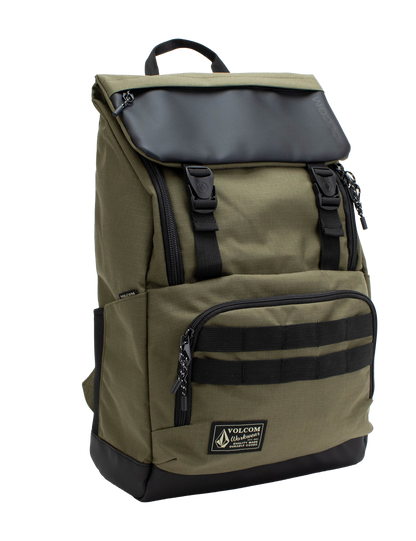 Men’s Charter Ruck Backpack by Volcom in olive green features a black flap, top handle, front zip pocket, and patch label. This workwear-inspired backpack has black straps, side pockets, and a rectangular silhouette shown against a white background.