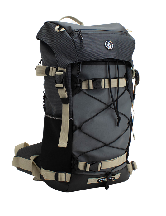 The Volcom Men's Peakstone Mountain Backpack is a durable gray and black daypack featuring beige straps, side pockets, a front bungee cord, and a top handle, shown against a white background.