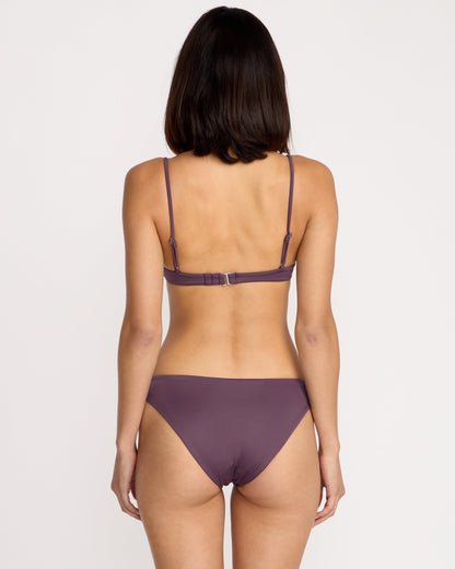A woman with shoulder-length dark hair is shown from the back, wearing a Volcom Women's Simply Seamless Vneck bikini in purple against a plain white background.