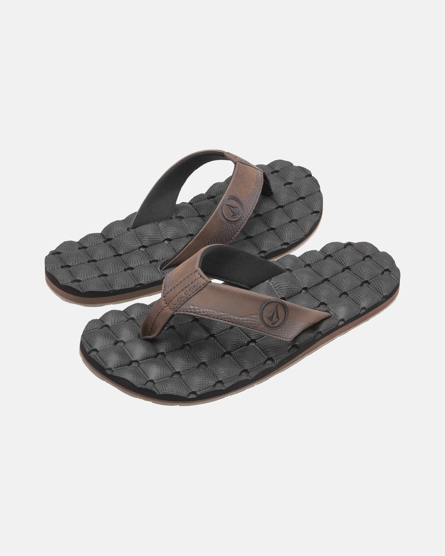A pair of Volcom Men's Recliner black flip-flop sandals with brown straps and woven textured, extra-grippy soles is displayed on a plain light background.