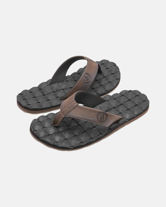 A pair of Volcom Men's Recliner black flip-flop sandals with brown straps and woven textured, extra-grippy soles is displayed on a plain light background.
