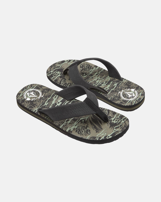 The Volcom Men's Daycation 2 Hawaii Sandals feature black straps and patterned soles with abstract green, beige, and black designs, plus a white circular logo near the heel on each sandal.