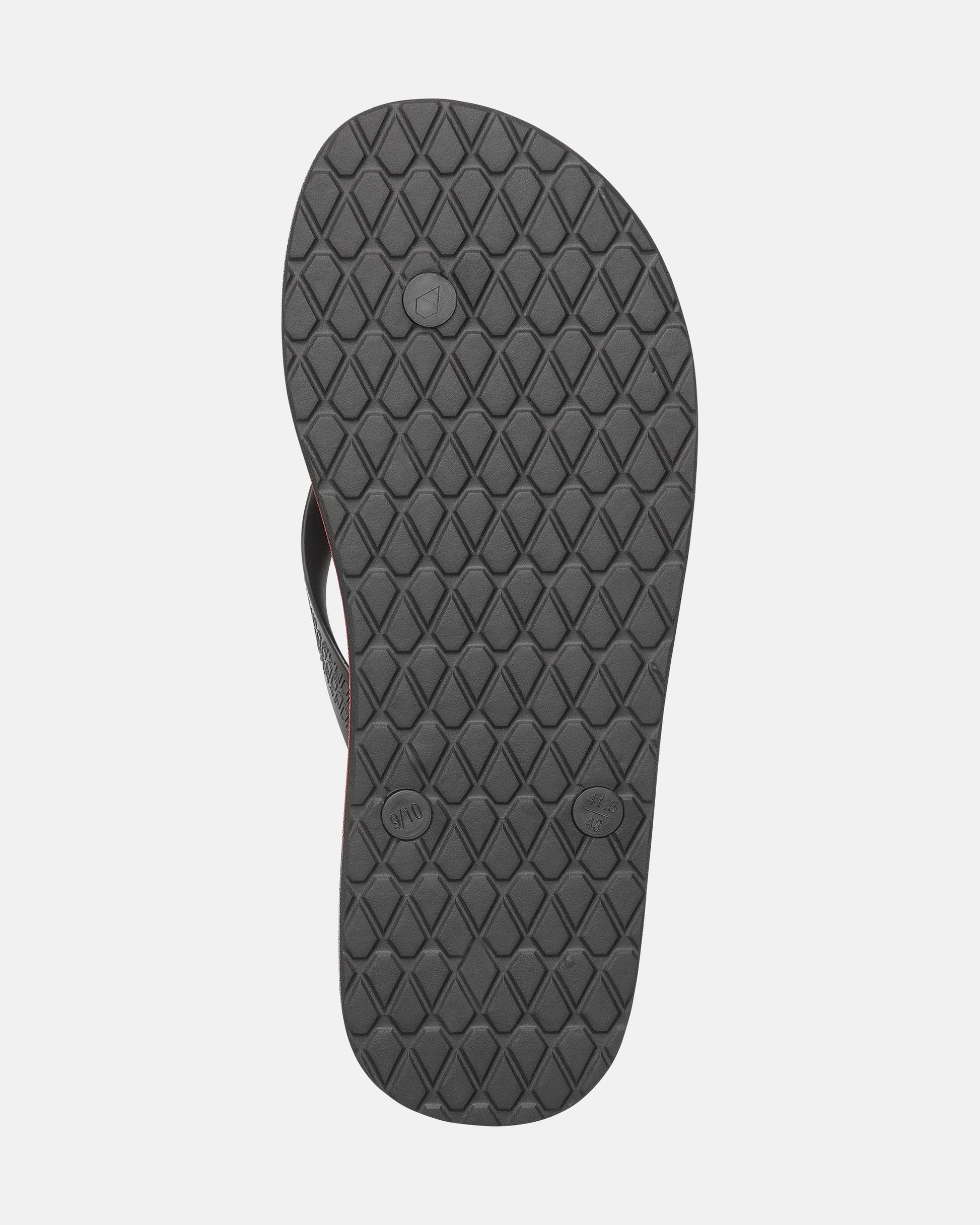 The image shows the bottom view of a single Volcomotion Mens flip-flop by Volcom, featuring a black, diamond-patterned textured rubber sole with circular markings on a plain light background.