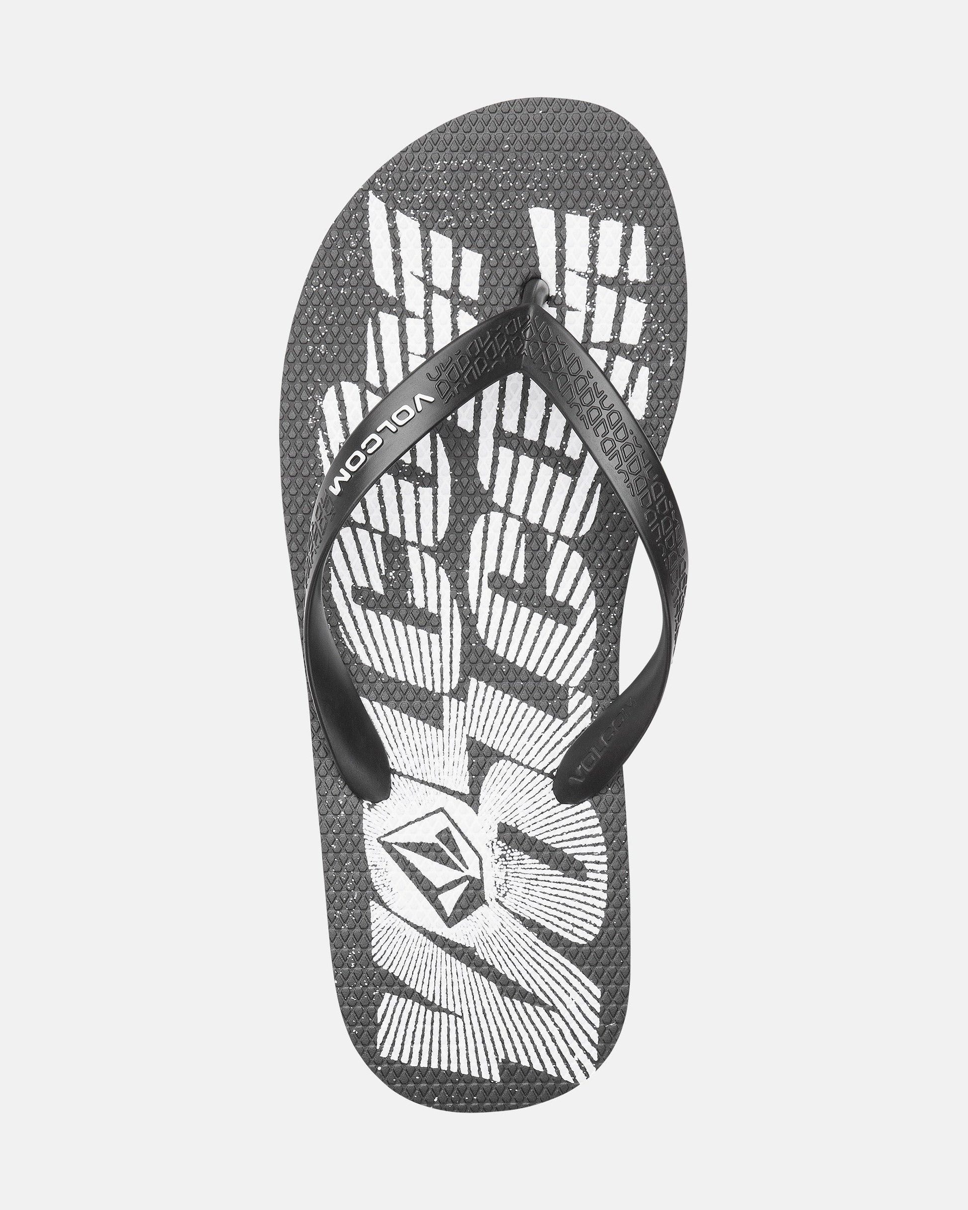 The Volcomotion Mens flip-flop by Volcom features a black textured sole, white abstract design, and VOLCOM branding on the strap and footbed.