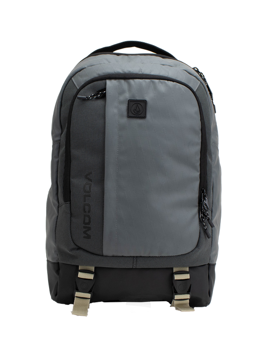 The Volcom Men's Venture Backpack features a gray design with a black bottom, front pocket, side zippers, and beige buckle straps. A small black logo patch accents the upper front. With a 22L capacity and padded laptop sleeve, this backpack offers a simple and functional style ideal for everyday use.