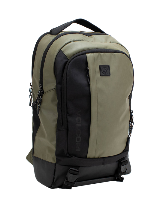 Introducing the Volcom Men's Venture Backpack in khaki and black, featuring a spacious 22L capacity with a front pocket, two side zippers, top handle, and a prominent black Volcom logo patch on the front. It includes a padded laptop sleeve for extra protection, a reinforced base for durability, and two bottom straps with buckles for added functionality.