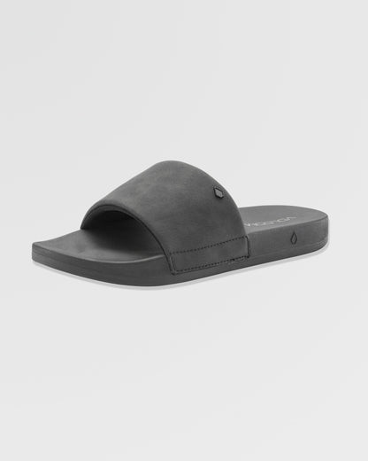 The Volcom Women's Volcation Slides are black summer sandals with wide straps and flat soles, designed for everyday comfort, shown at a slight angle on a plain white background.