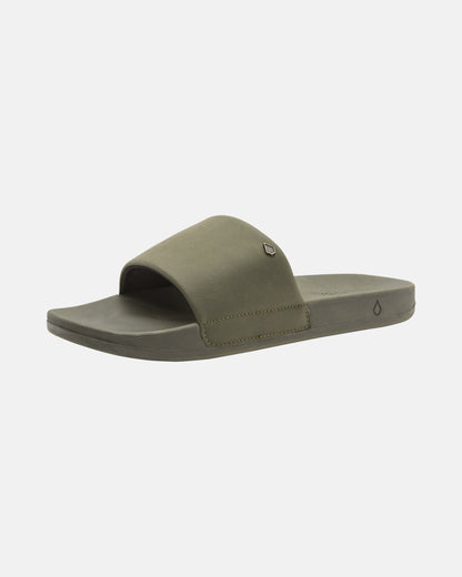 The Volcom Women's Volcation Slides feature an olive green wide strap and flat sole, offering everyday comfort and effortless style—perfect summer sandals shown on a white background.