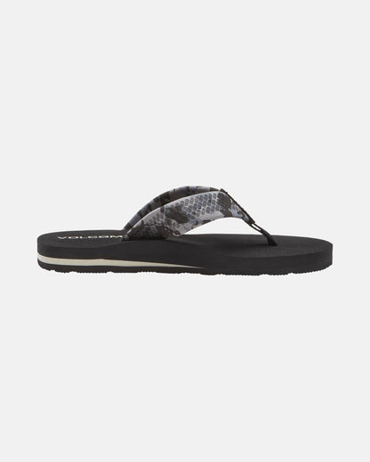 The Volcom Kids' Daycation 2 Big Youth sandal features a flat sole, cushioned Recliner Comfort Foam, and a black translucent strap with a gray snake-like pattern. The Volcom logo is partially visible on the footbed near the heel.